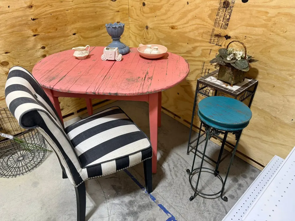 Weathered coral-painted table with ceramic pieces beside a small accent table