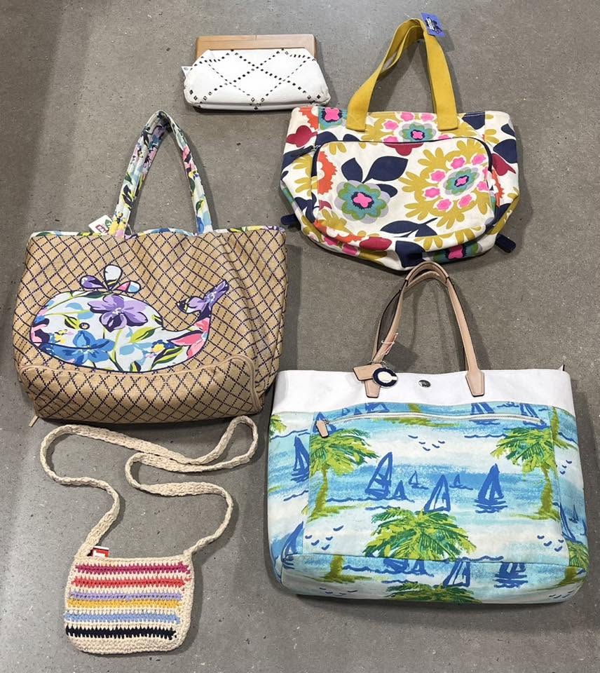 Colorful patterned tote bags and crossbody purses, including a whale-print tote and a palm-tree print bag, laid out on the floor