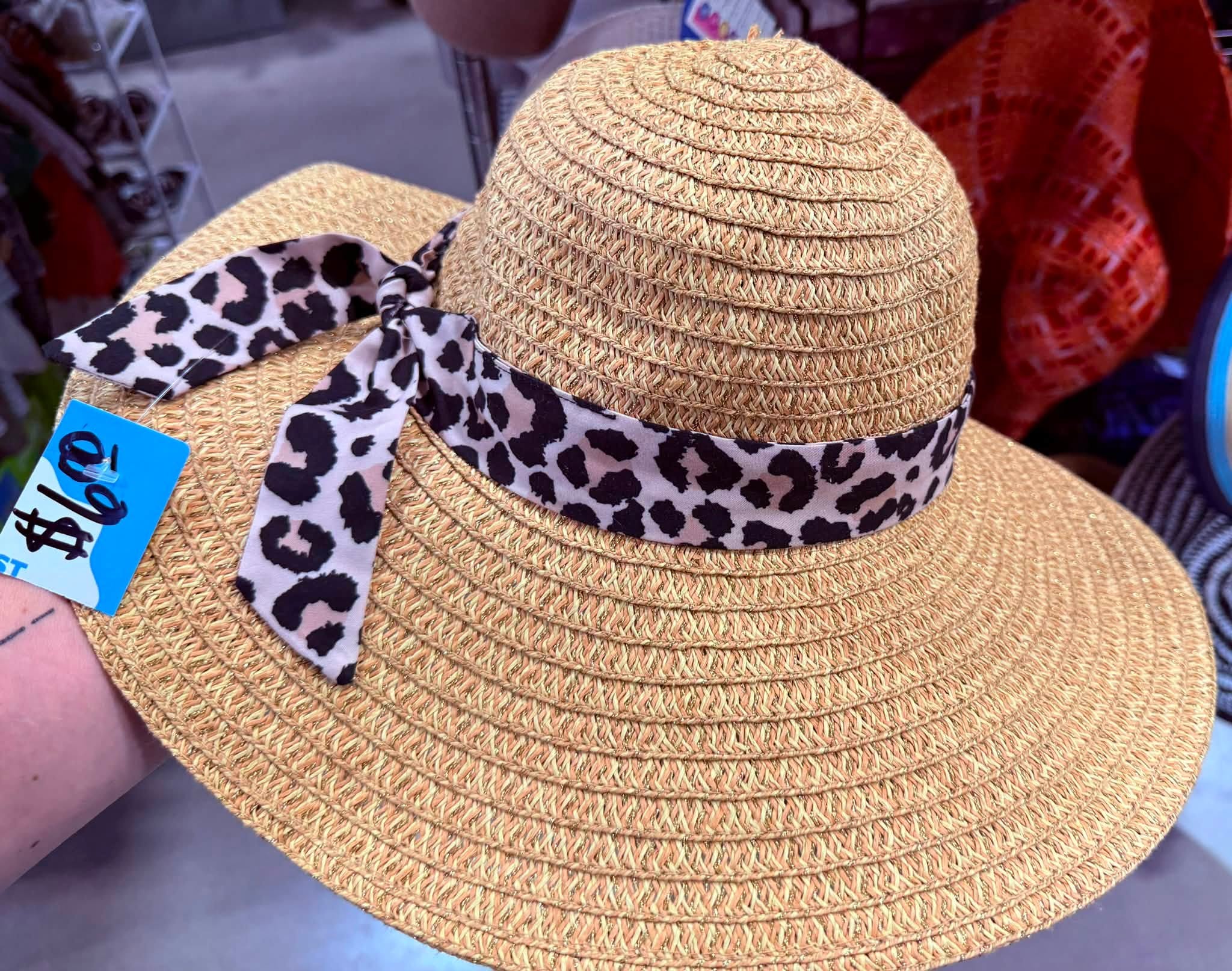Close-up of a woven straw sun hat with a leopard-print ribbon tie