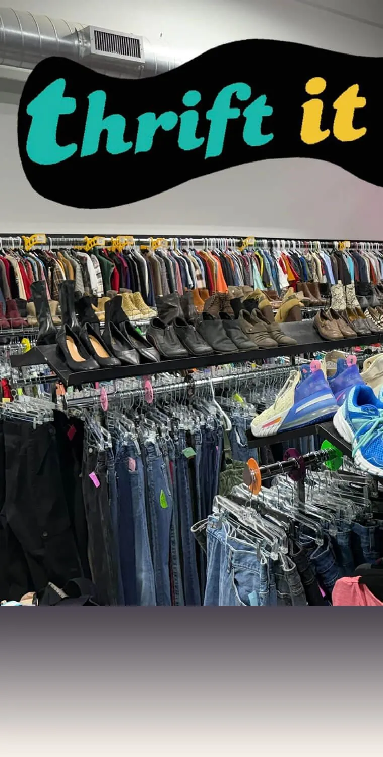 Inside the Thrift It Out store, with the shop's wavy logo on the wall above racks of clothing, shoes and jeans
